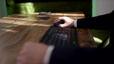 Person im Anzug tippt auf einer Tastatur am Bürotisch
