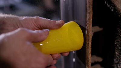 Hand füllt gelben Plastikbecher mit fließendem Wasser