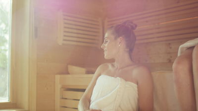 Frau entspannt in der Sauna im warmen Licht, Frau in der Sauna, Sauna Wellness und Saunagang als 4K Stockvideo