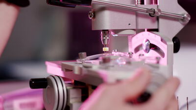 Hand bedient ein Präzisionsinstrument im Labor bei rosa Licht