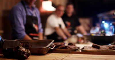 Dunkel gewürztes Grillfleisch vor unscharfem Hintergrund bei einem Grillkurs