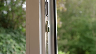 Blick durch ein gekipptes Fenster in den grünen Garten