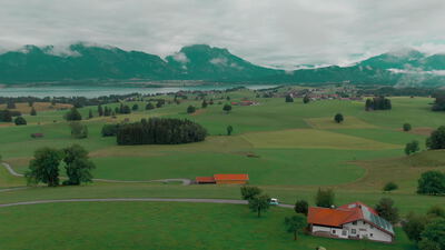Drohnenflug über grüne Wiesen und einen See im Alpenvorland, Drohnenaufnahme, Luftaufnahme und Landschaft als 4K Stockvideo