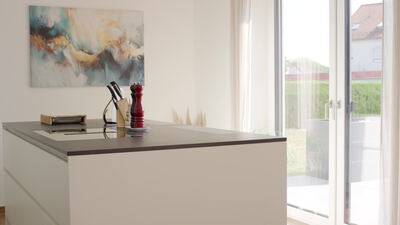 Moderne helle Küche mit großen Fenstern und Kücheninsel