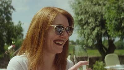 Frau mit roten Haaren genießt Weißwein an einem Sommertag