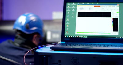 Techniker liest Messsoftware auf einem robusten Laptop im Prüflabor