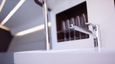 Verchromter Wasserhahn über weißem Waschbecken in eleganter Umgebung