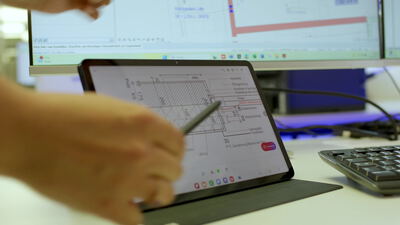 Hände bedienen Tablet mit technischen Daten im Büro