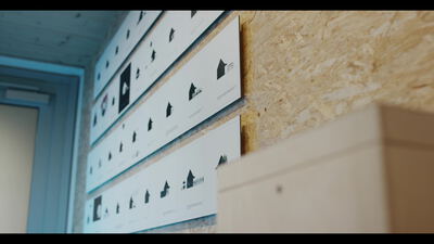 Bedrucktes Piktogrammblatt an einer Wand aus Grobspanplatte