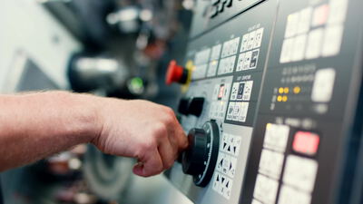 Facharbeiter bedient Steuerungspult einer CNC Werkzeugmaschine