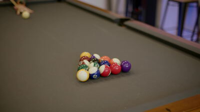 Bunte Billardkugeln liegen nach dem Anstoß verteilt auf dem grünen Pooltisch