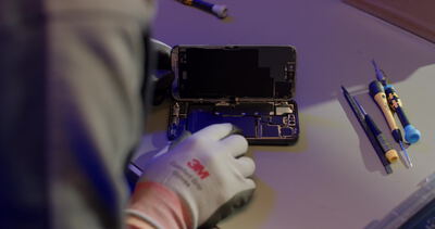 Smartphone Reparatur mit Werkzeug am Arbeitsplatz in der Werkstatt