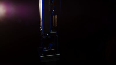 Metallisches Bauteil in blauem und rosa Licht vor dunklem Grund