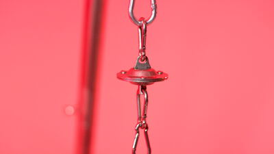 Verchromter Schnapphaken und roter Metallbeschlag auf rosa Grund