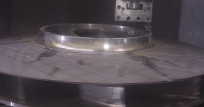 Glänzende Metallscheibe rotiert unter einem Messinstrument in der Fertigung