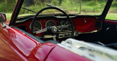 Cockpit eines roten Oldtimer Sportwagens mit Lenkrad und Armaturen