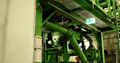 Grüne Rutsche und Rohre unter einer Recyclinganlage von unten