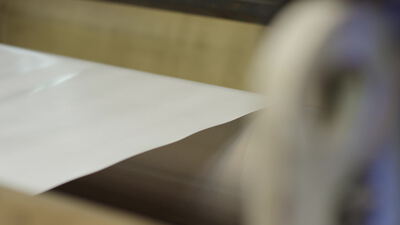 Weiße Materialbahn wickelt sich von der Walze ab, Abwickeln, Produktionsmaschine und weiße Bahn als 4K Stockvideo