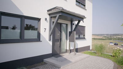 Moderne Haustür eines Einfamilienhauses mit Vordach und Edelstahlgeländer