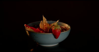 Gesunde Müslischale mit Erdbeeren und Physalis vor dunklem Hintergrund