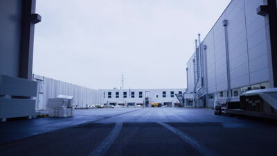 Große Industriehalle mit leerem Hof unter bewölktem Himmel