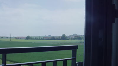 Ausblick vom Balkon über grüne Felder bis zum Dorf am Horizont