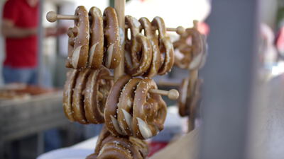 Frische Brezeln hängen an Holzstäben an einem Marktstand