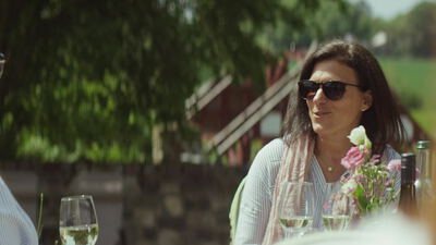 Frau mit Sonnenbrille im Gespräch bei einem sommerlichen Gartenessen
