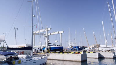 Segelyachten liegen im Hafen vor einem weißen Bootskran