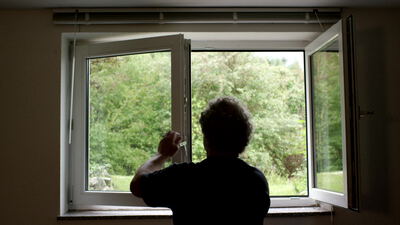 Person öffnet ein Fenster zum Lüften im Wohnraum