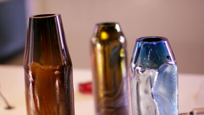 Drei schillernde Glasvasen in Handarbeit auf hellem Tisch