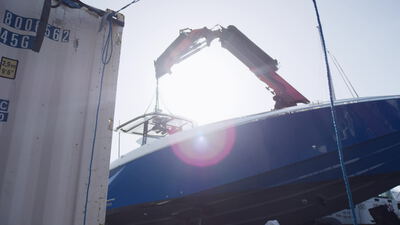 Roter Hydraulikkran hebt eine blaue Motoryacht auf der Bootswerft