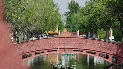Rote Bogenbrücke über einen Teich im asiatischen Tempelpark