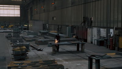 Weite dunkle Industriehalle mit Metallbearbeitung und Funkenflug
