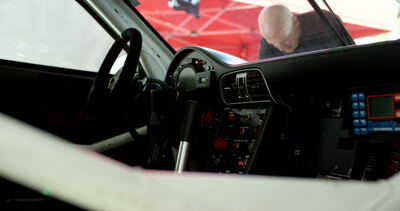 Cockpit eines Autos zeigt Lenkrad, Armaturenbrett und blaues Bedienpanel