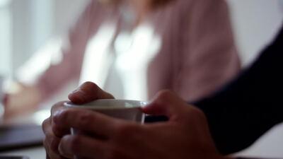 Hände halten eine warme Tasse am hellen Fenster