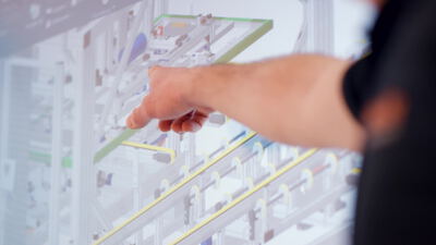 Hand zeigt auf digitale Anlagensimulation am Bildschirm