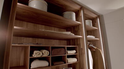 Blick in einen Einbauschrank aus Nussbaumholz mit Regalen und Hemden