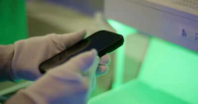 Techniker bedient Smartphone mit Handschuhen unter grünem Licht Techniker bedient Smartphone mit Handschuhen unter grünem Licht, Smartphone bedienen, Techniker Handschuhe und