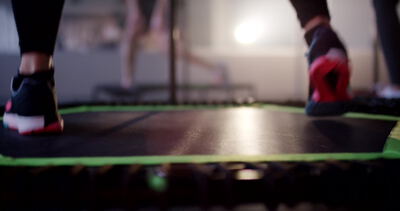 Nahaufnahme bunter Sneaker beim Trampolinspringen im warmen Licht
