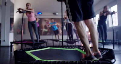 Fitnessgruppe springt beim Jumping Fitness Training unter bunter Discokugel