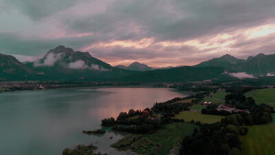 Luftaufnahme eines Alpensees vor Bergen in der Abenddämmerung