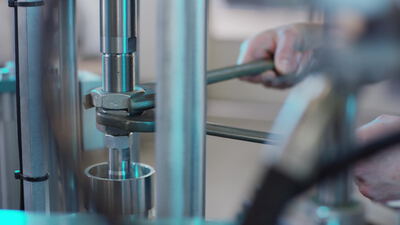 Techniker justiert eine Abfüllmaschine aus Edelstahl mit dem Schraubenschlüssel