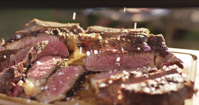 Salzflocken fallen auf saftig gegrilltes Steak in Scheiben