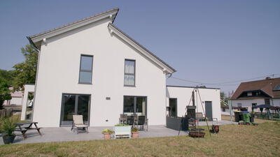 Modernes weißes Einfamilienhaus mit Garten und Terrasse von hinten