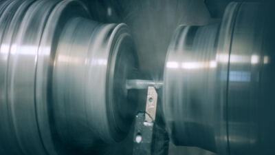 Drehmaschine bearbeitet rotierendes Metallwerkstück in Großaufnahme Drehmaschine bearbeitet rotierendes Metallwerkstück in Großaufnahme, drehmaschine metallbearbeitung, metallwerkstück drehen