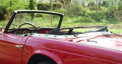 Seitenpartie eines roten Oldtimer Cabrios mit offenem Verdeck