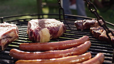 Steaks und Bratwürste brutzeln auf einem Schwenkgrill im Garten