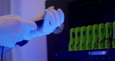 Fachkraft montiert Elektronik unter blauem Licht in der Fertigung