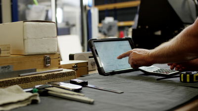 Hand bedient ein Tablet an einem Werkstatttisch